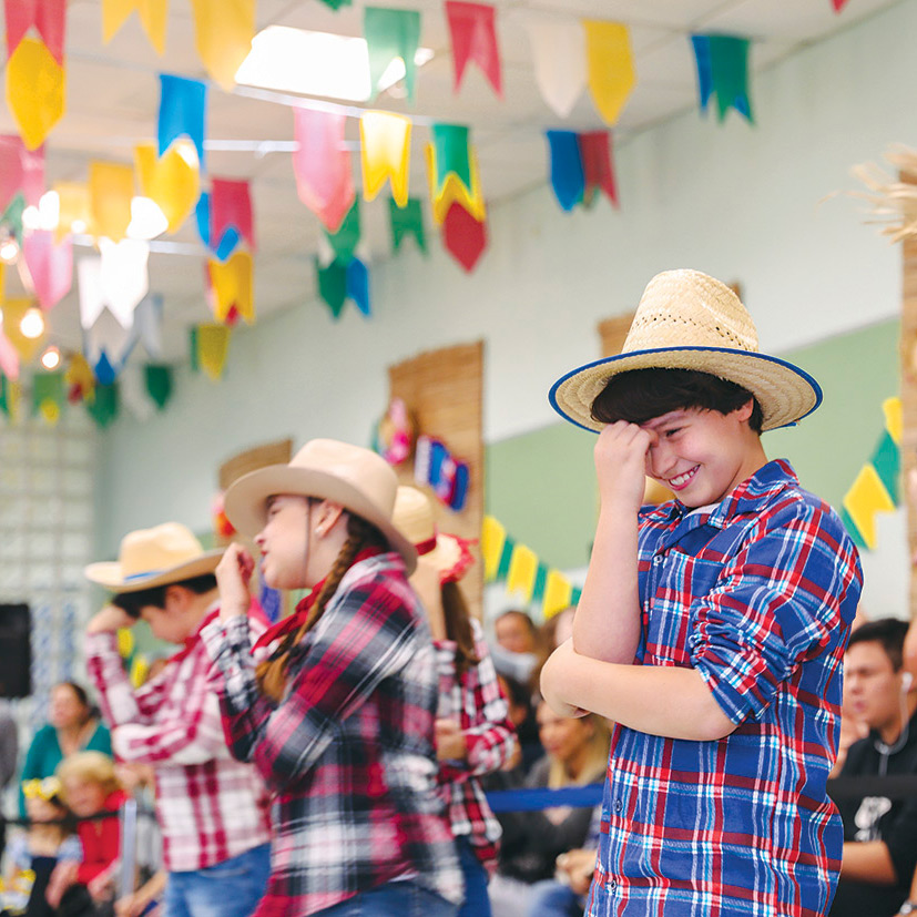 Foto de alunos do Objetivo dançando em uma festa junina.